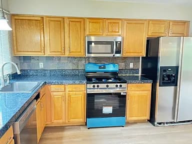 Kitchen with light cabinets, blue countertops, and stainless appliances